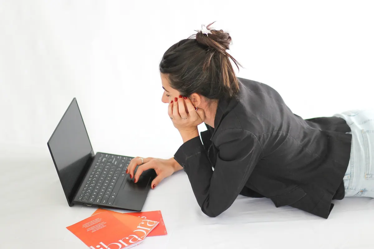 Pía trabajando en su computadora recostada en el piso