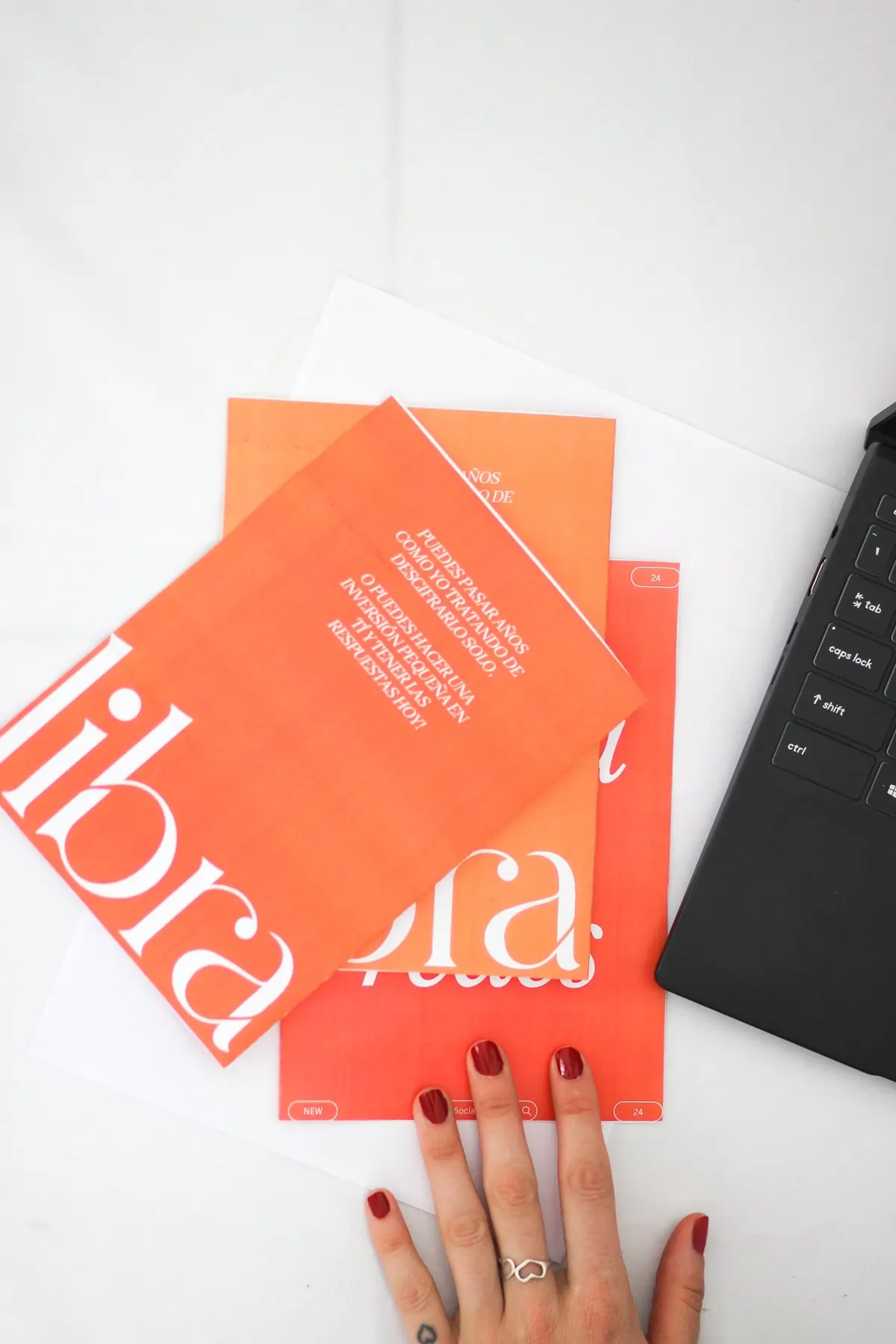 Cuadernillos naranjas de Libra junto a una computadora